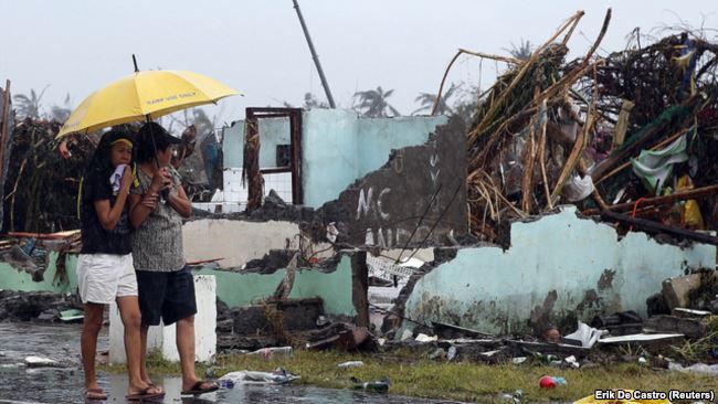 Women share an umbrella as they look at a house that was destroyed after Super Typhoon Haiyan hit Tacloban in central Philippines.