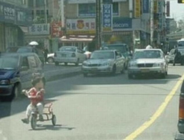 I'm outta here: Perhaps terrified of what might be coming next, this little trike rider from somewhere in the Far-East is striking out on his own