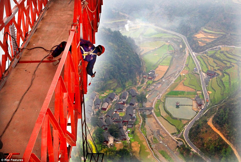 Dizzying: Labourers put the finishing touches to the Anzhaite Long-span Suspension Bridge in Jishou, Hunan, China, this week, just in time for its opening