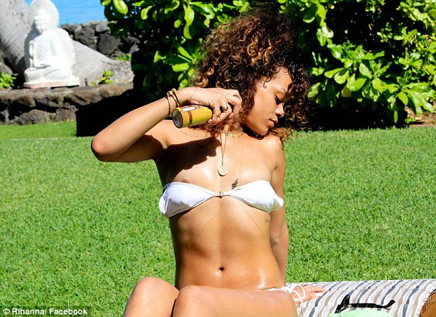 Protect yourself: The Bajan singer practises safe sun as she sprays herself with SPF