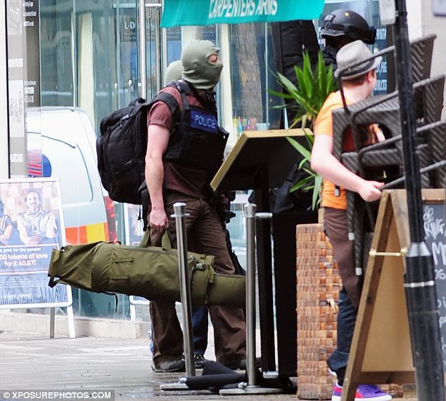 Armed to the teeth: As a cafe worker looks on in surprise, Met police snipers arrive with weapons stowed in holdalls to get into position on rooftops around Tottenham Court Road