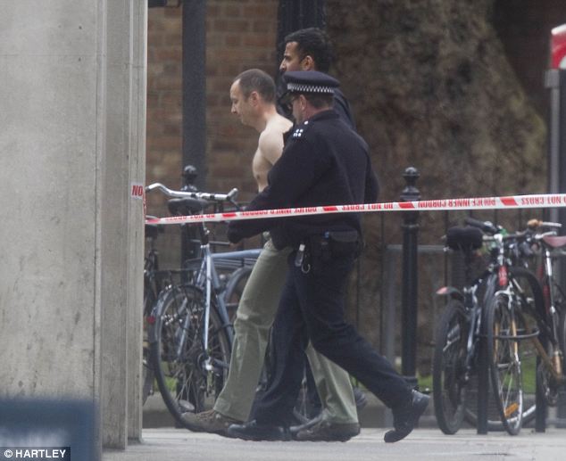 Apprehended: Regular officers lead away the suspect, unharmed but cuffed and stripped to the waist, after the massive police operation this afternoon