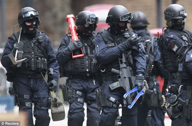 Combat team: Tooled up and ready to raid the building, armed officers are seen on Tottenham Court Road. Special forces and police firearms units have trained together in urban warfare tactics